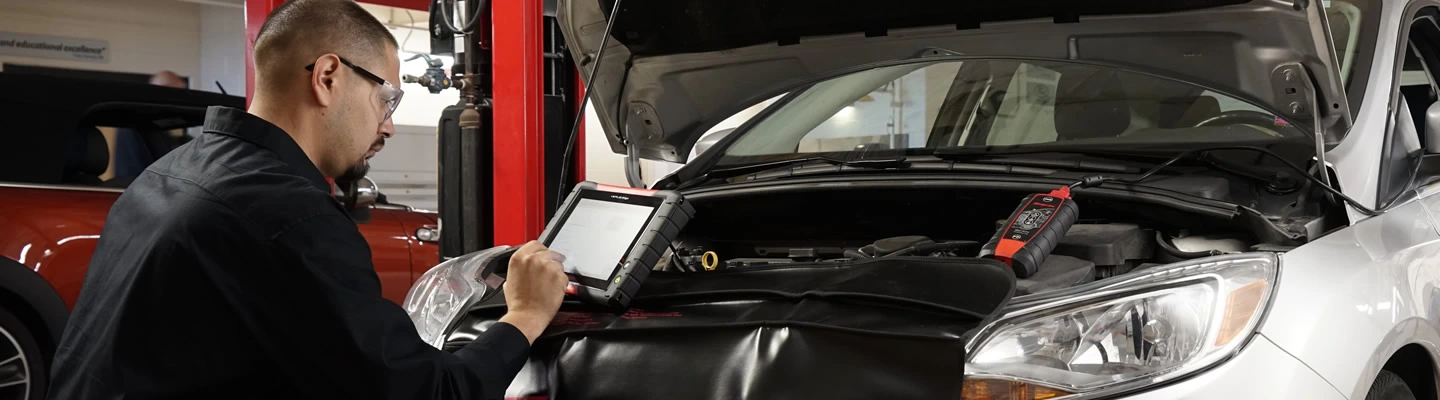 Automotive technition working under the hood of a vehicle using a VERUS Edge diagnostic scan tool and Intelligent Diagnostics